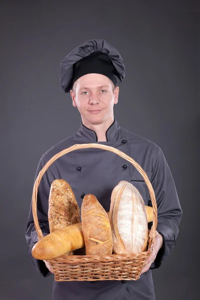 Chef profesional en un traje gris sosteniendo una cesta de pan —  Fotos de Stock