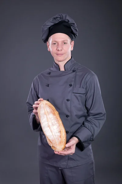 Koki profesional dalam setelan abu-abu memegang roti di tangannya — Stok Foto