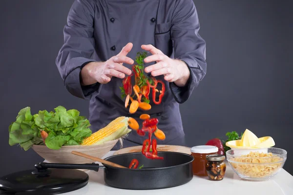 Professionele chef-kok gooit voedsel in de pan — Stockfoto