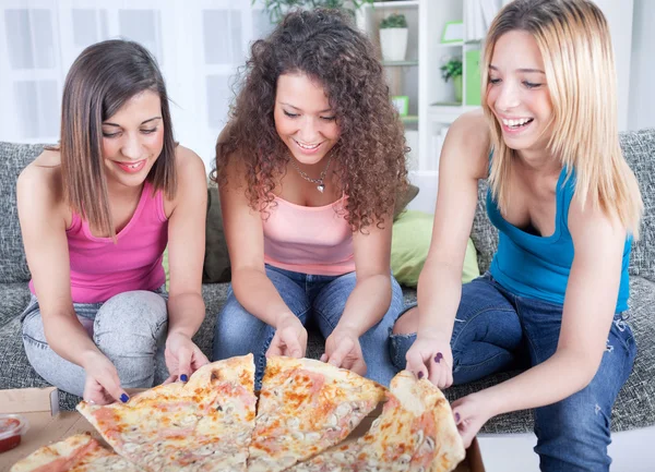 Três alegre jovem mulher comer pizza em casa — Fotografia de Stock