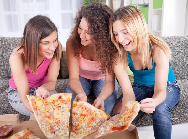 Drei fröhliche junge Frau, die zu Hause Pizza isst — Stockfoto