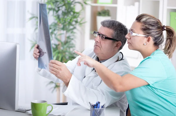 Senior male radiologist and female patient looking at x-ray — Stock Photo, Image