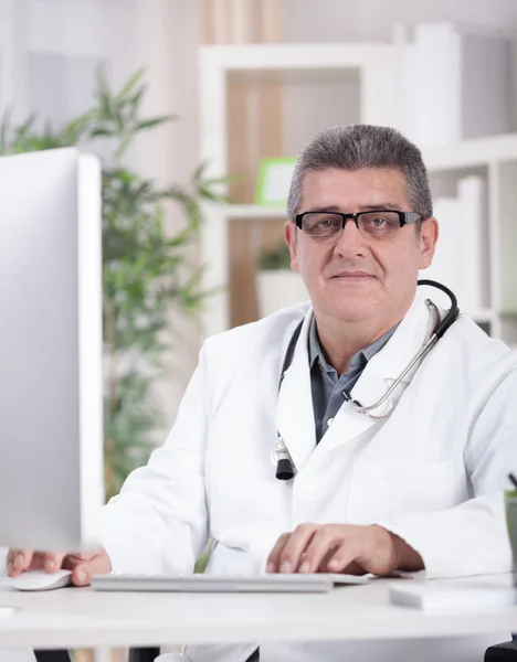 Lächelnder moderner Oberarzt mit Brille im Büro — Stockfoto