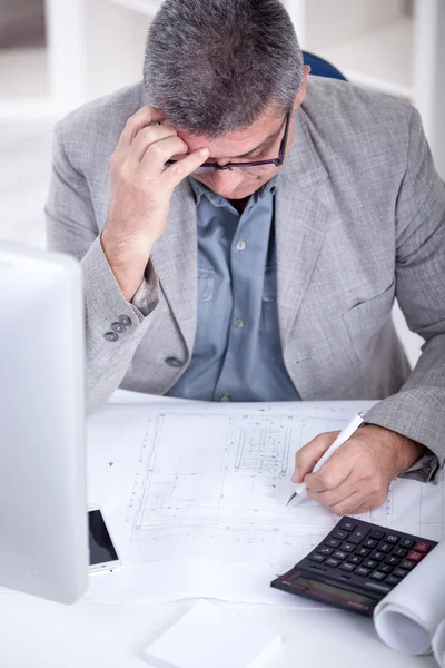 Architect working on construction blueprint in office — Stock Photo, Image