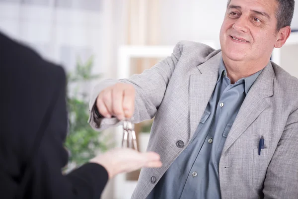 Hombre de negocios senior entrega de llaves al hombre —  Fotos de Stock