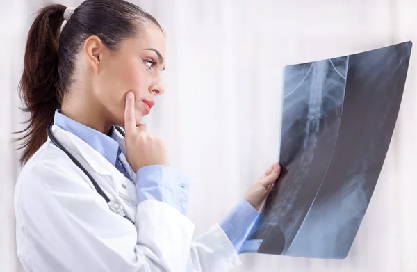 Beautiful young woman orthopedist examine X-rays — Stock Photo, Image