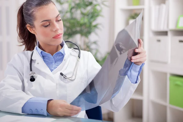 Beautiful young woman orthopedist examine X-rays — Stock Photo, Image