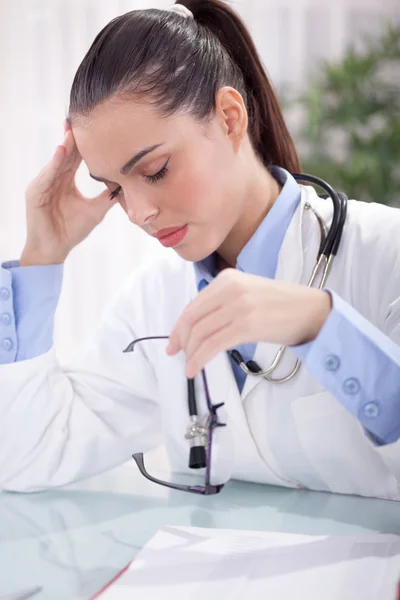 테이블에 앉아서 들고 닫힌된 눈을 가진 여성 의사 — 스톡 사진