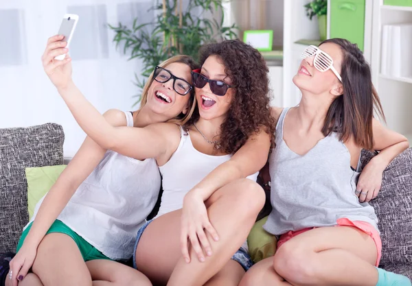 Skupina tří přítelkyň, baví se smartphony — Stock fotografie