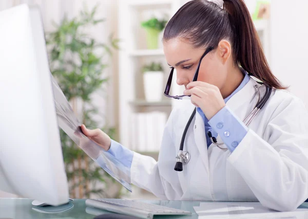 Beautiful young woman orthopedist examine X-rays — Stock Photo, Image