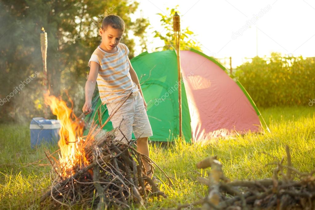 boy on a camping trip  baking sausage