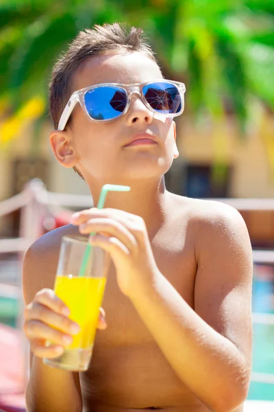 Niño con gafas de sol en la playa disfruta y mantiene el jugo —  Fotos de Stock