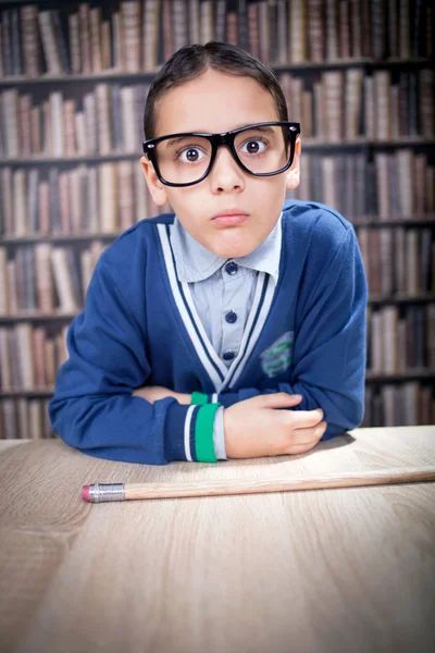 Śmieszne młody naukowiec, hustler w okularach w bibliotece — Zdjęcie stockowe