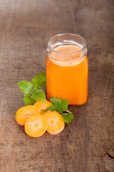 Φρεσκοστυμμένο χυμό καρότα σε ξύλινα φόντο — Φωτογραφία Αρχείου