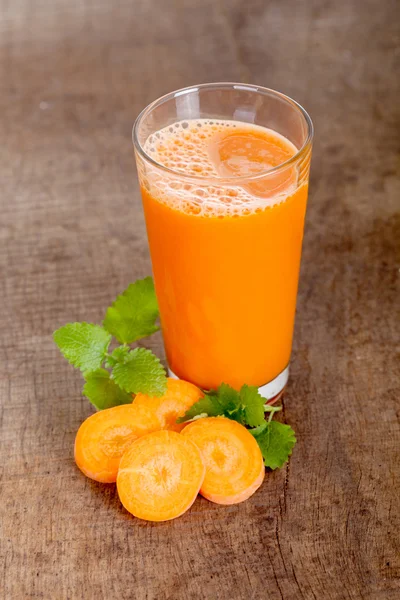 Φρεσκοστυμμένο χυμό καρότα σε ξύλινα φόντο — Φωτογραφία Αρχείου