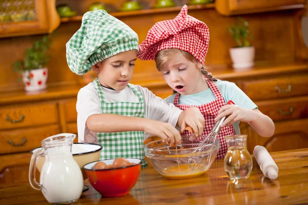 Dvě děti připraví vejce pro soubory cookie v kuchyni — Stock fotografie