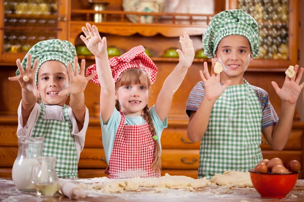 Drei lustige kleine Kinder spielen mit einem Teig in der Küche — Stockfoto