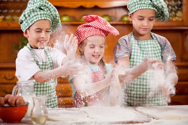Τρία αστεία μικρό παιδί χειραψία με αλεύρι στην κουζίνα — Φωτογραφία Αρχείου