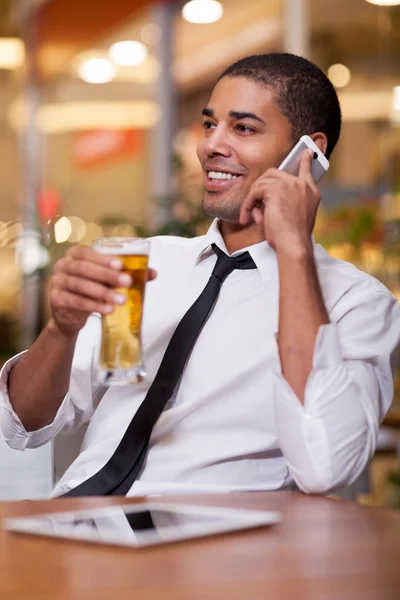 Homme d'affaires détendu dans un restaurant boire de la bière et parler sur — Photo