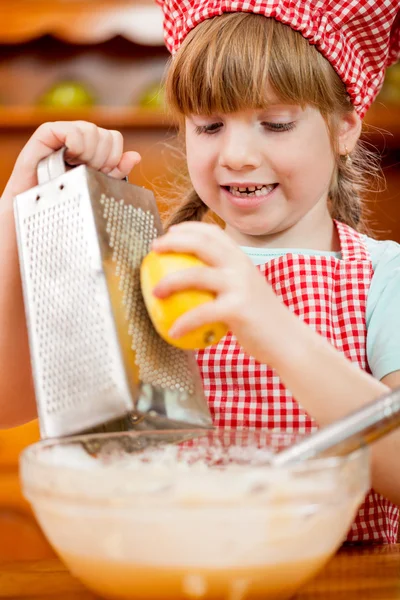 Petite fille dans la cuisine raboteuses écorce de citron — Photo