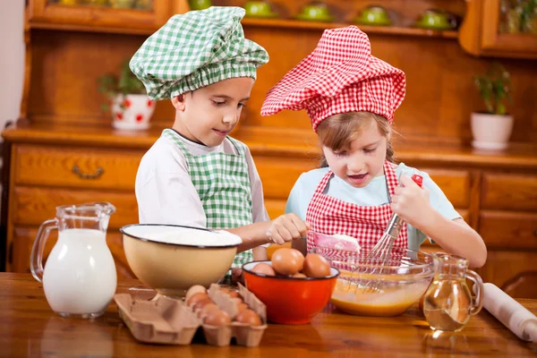 Dvě šťastné děti připraví vejce pro soubory cookie v kuchyni — Stock fotografie