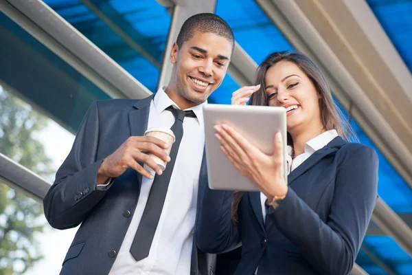 Junge lächelnde erfolgreiche Geschäftsleute mit Tablet-Computer-Geschwätz — Stockfoto