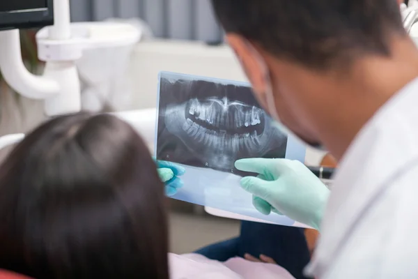 Närbild av tandläkare förklara detaljerna i röntgen bild till Hej — Stockfoto