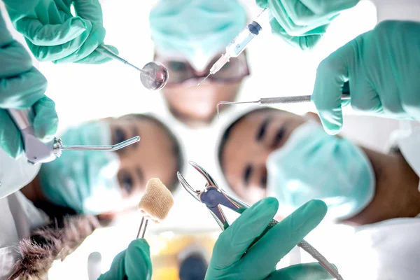 Equipe dentária trabalhando com um paciente em desgaste de trabalho de proteção — Fotografia de Stock