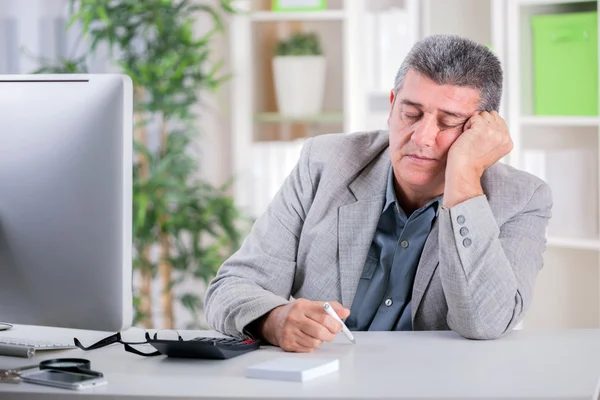 Överarbetade affärsman sover vid skrivbordet — Stockfoto