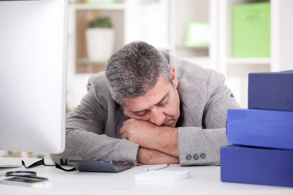 Trött senior affärsman sover vid skrivbord i office — Stockfoto