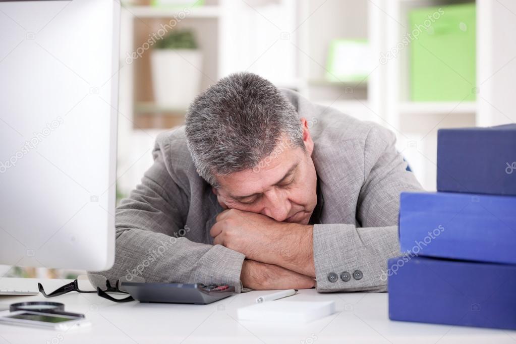 tired senior businessman sleeping at desk in office