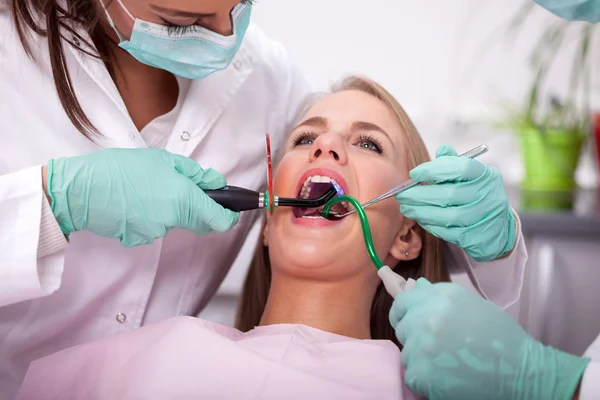 Dentista está tratando los dientes de la paciente femenina — Foto de Stock