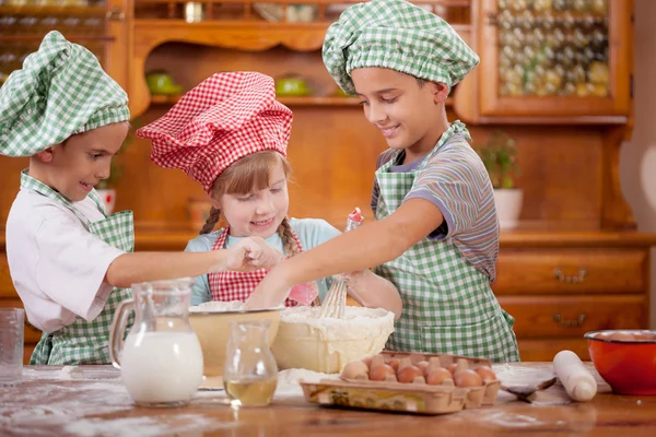 Three funny young child mix dough in the kitchen — Stock Photo, Image