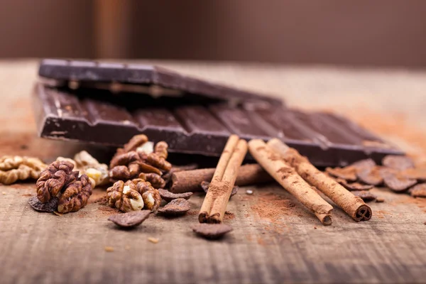 Coklat gelap dan kayu manis menempel pada latar belakang kayu — Stok Foto