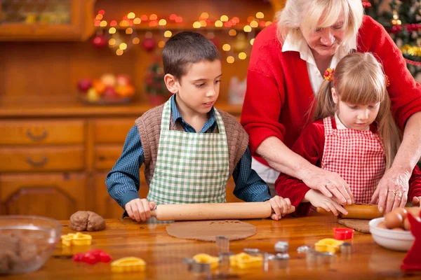 grandmother and little girl and boy baking Christmas cakes in th
