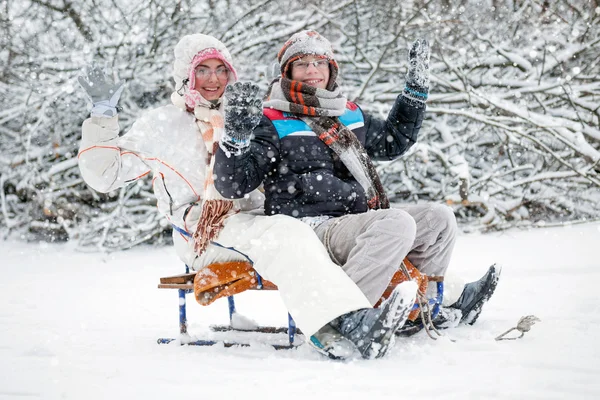 Διασκέδαση χειμώνα, αγόρι και ένα κορίτσι με έλκηθρο στο χειμώνα — Φωτογραφία Αρχείου