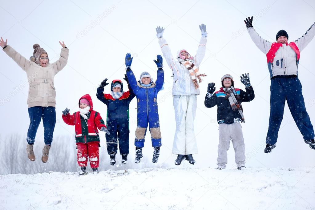 a group of children, women and men jumping in the air at snowy w