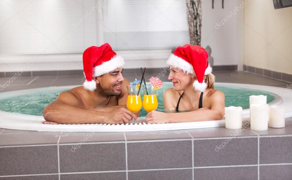 Beautiful woman and man with santa hat relaxing in jacuzzi at sp