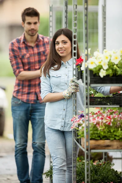 Young smiling florists man and woman working in the greenhouse — Stock Photo, Image