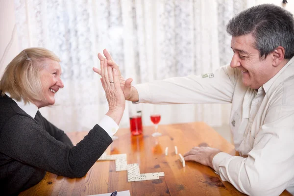 Happy senior people in retirement home playing domino game — Stock Photo, Image