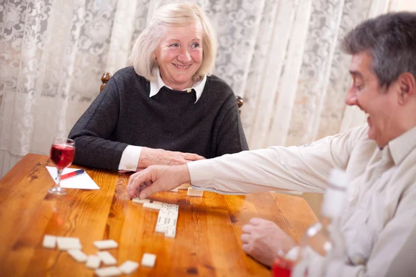 Happy senior people in retirement home playing domino game — Stock Photo, Image