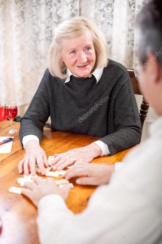 Couple playing dominoes in living room smiling
