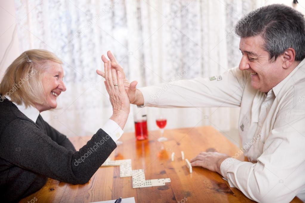 happy senior people in retirement home playing domino game