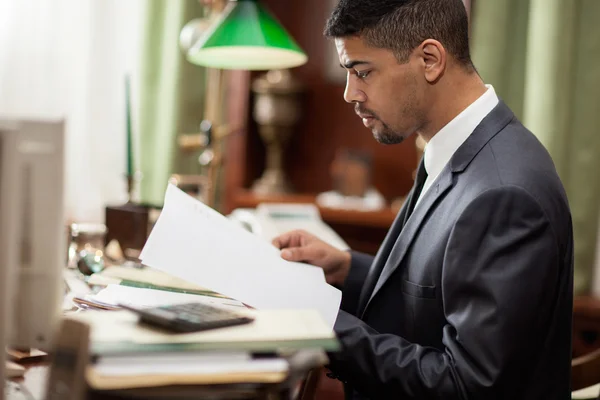 Zakenman zitten aan een tafel in het kantoor en ik lees een impor — Stockfoto