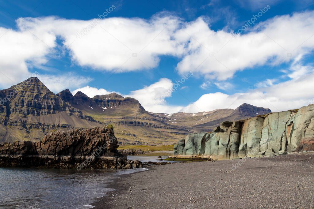 Different colored and textured mountains near the Atlantic ocean. East Iceland coastline. Summer road trip.
