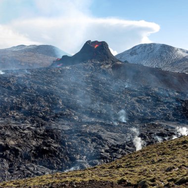 Kar yağışı sonrası dumanı tüten lav. Fagradalsfjall, İzlanda 'daki volkanik patlamanın dramatik bir fotoğrafı. Volkanın atmosferik fotoğrafı.