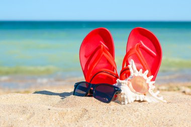 Terlik, güneş gözlüğü ve kabuk kum