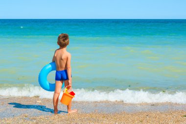 Oyuncaklar, çocuk denize bakarak