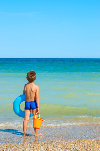 Child with toys, looking at the sea