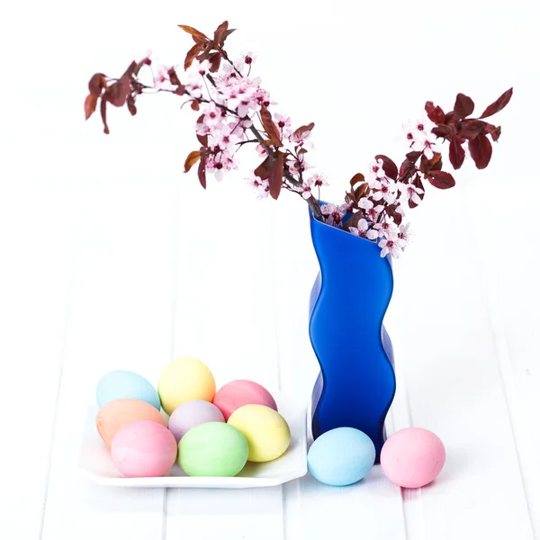 Easter eggs on plate with blooming branch — Stock Photo, Image